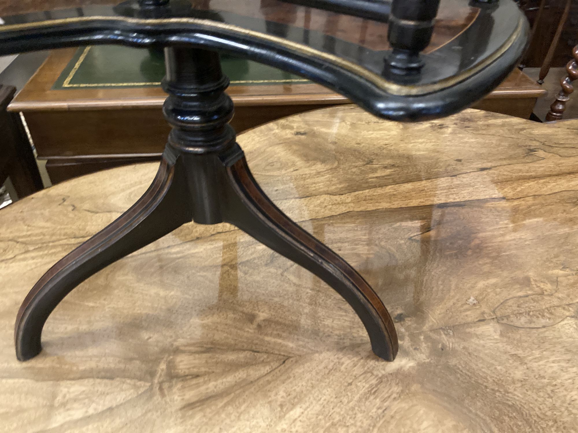 An ebonised and gilt thuya or walnut book table, the circular top over revolving trefoil book rack